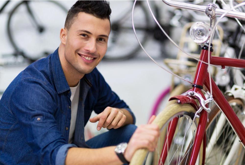 Ragazzo felice che fa la manutenzione a una bicicletta facilmente grazie al software gestionale per noleggi bici RENT-ALL