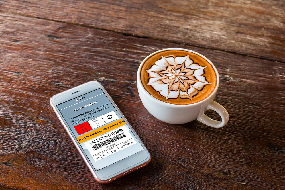 Cup of cappuccino with cell phone on the side that monitors your turn thanks to the RENT-ALL checkin